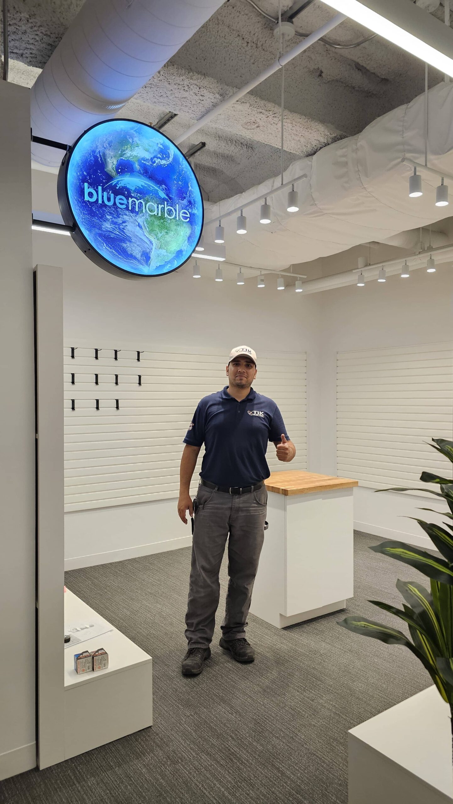 Electrician in modern retail space under round LED sign — evenly spaced track lighting