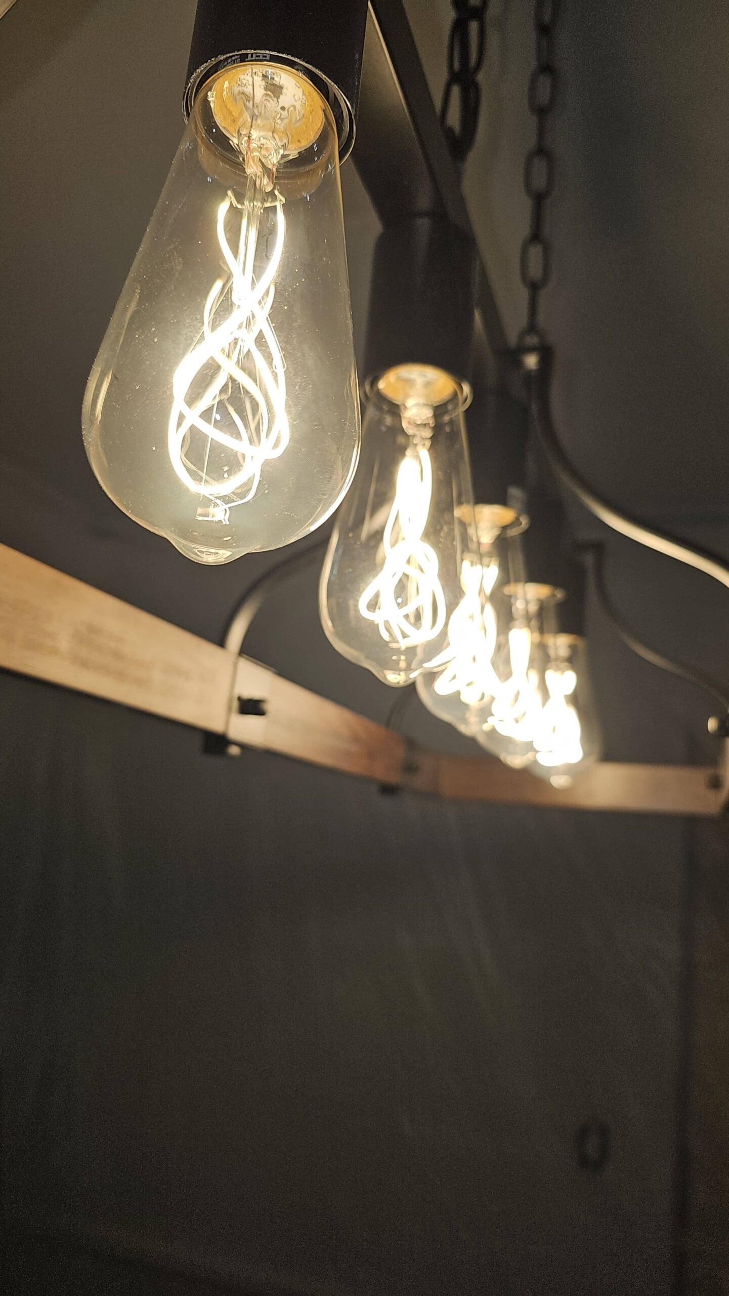 Close-up of warm Edison-style pendant bulbs on wooden fixture — soft ambient glow